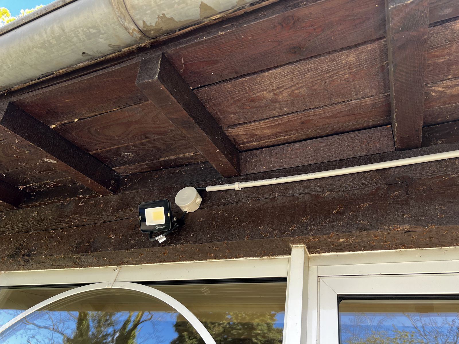 Projecteur installé sous une pergola avec cheminement en conduit